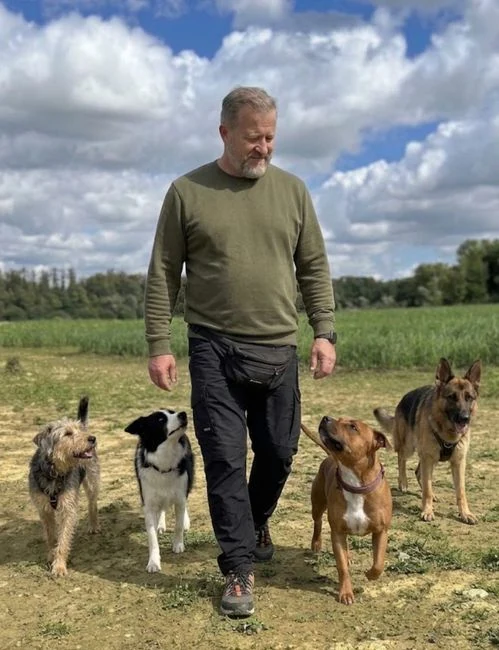 Mike geht mit vier aufmerksamen Hunden über einen Feldweg